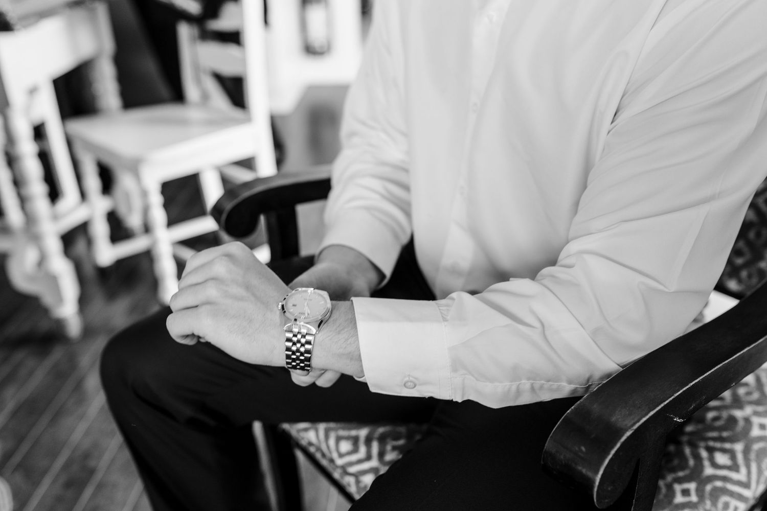 Formal white dress shirt sleeve with geometric pattern chair in background.