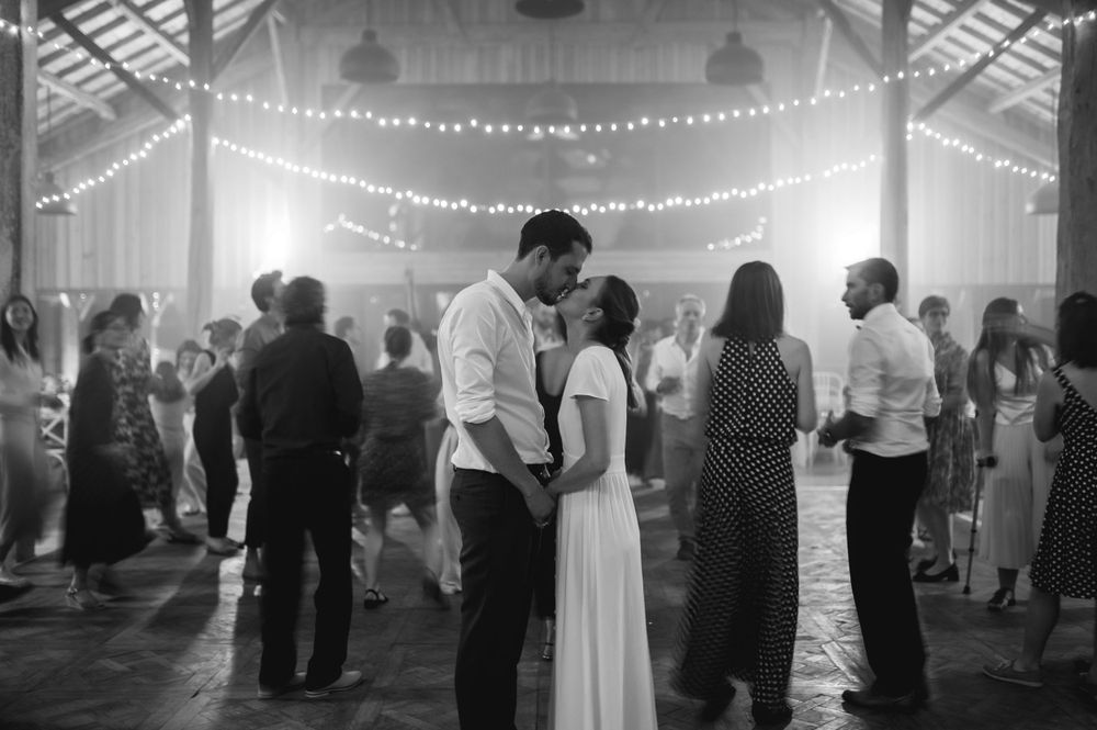 Wedding celebration in a spacious barn with twinkling lights strung across the ceiling.
