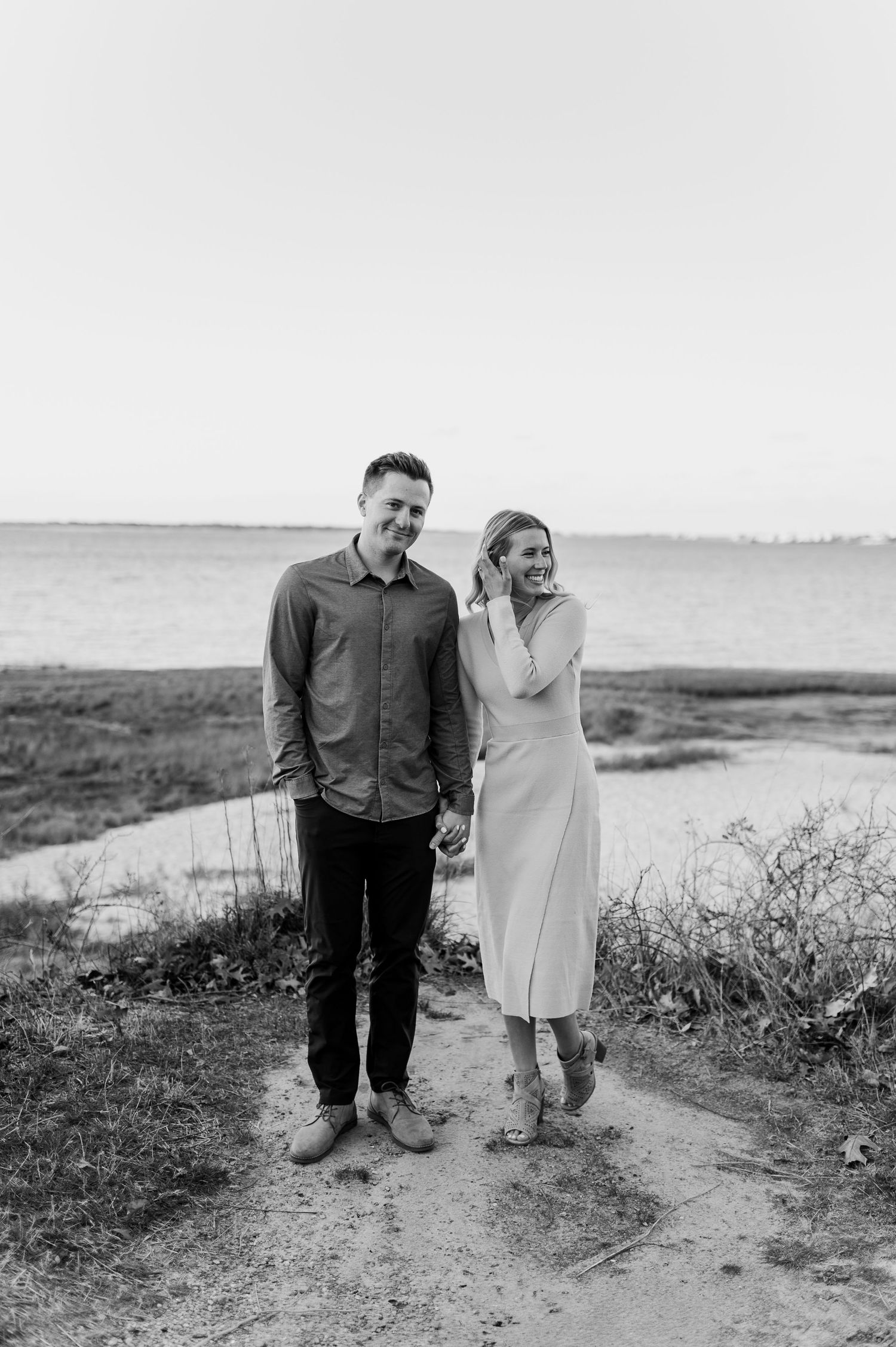 Black and white photo of couple standing together on coastal path.