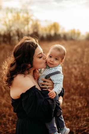 Mother holding her baby boy in a fall field during a motherhood photo session in Branson, MO by L. Ballenger Photography.
