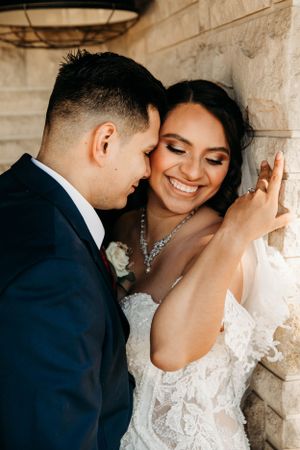 Close-up of an emotional bride and groom leaning against a stone wall by Branson, MO Photographer L. Ballenger Photography.