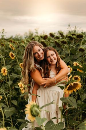 Mother and daughter hugging in a field of sunflowers during a late summer photo session in Branson with L. Ballenger Photography.