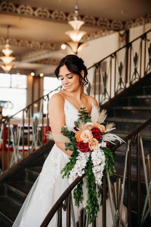 Stunning bride posing on a grand staircase at a wedding venue, photographed by Branson, MO Photographer L. Ballenger Photography.