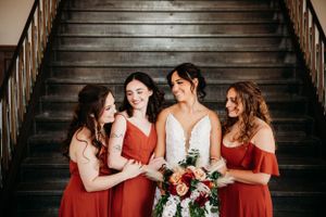 Bride laughing with her bridesmaids in rust-colored dresses on a staircase, photographed by Branson, MO Photographer L. Ballenger Photograph