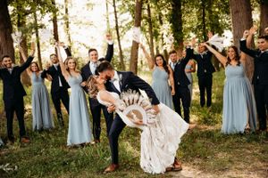 Wedding party cheering as the bride and groom kiss outdoors at a venue by Branson, MO Photographer L. Ballenger Photography.