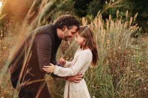 Father-daughter hugging in a field of tall grass during an autumn photoshoot in the Ozarks with L. Ballenger Photography.