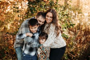 Family of four posing in a wooded autumn field for a fall photoshoot with L. Ballenger Photography.