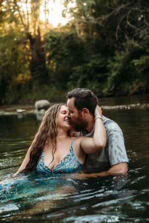 Romantic couple embracing in the water of a Branson, MO creek during a lifestyle photo session with L. Ballenger Photography.
