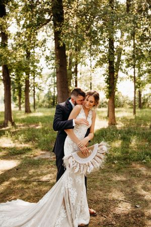 Bride and groom sharing a first dance in a sun-lit forest at a Branson elopement, photographed by L. Ballenger Photography.