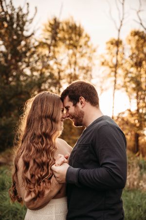 Couple sharing a quiet moment in a sun-lit forest for a romantic photo session in Branson, Missouri by L. Ballenger Photography.
