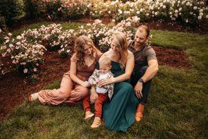 Family of four sitting in a lush flower garden during a summer photo session in Branson.