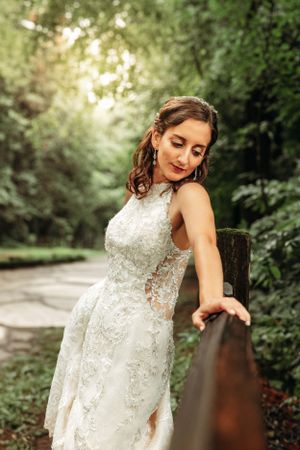 Stunning bridal portrait of a woman in a lace gown leaning on a rustic bridge, captured by Branson, MO Photographer L. Ballenger Photography