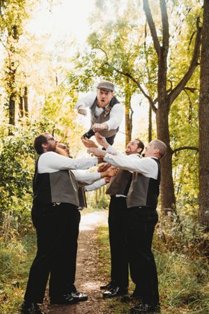 Fun groomsmen portrait of men lifting the groom in the Branson woods by Branson, MO Photographer L. Ballenger Photography.