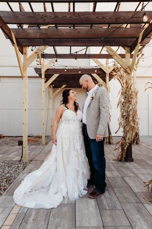 Destination wedding couple posing under a rustic wooden pergola by Branson, MO Photographer L. Ballenger Photography.