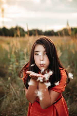 Childblowing confetti in a golden hour field during a Branson, MO photo session by L. Ballenger Photography.
