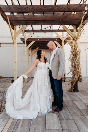 Destination wedding couple posing under a rustic wooden pergola by Branson, MO Photographer L. Ballenger Photography.