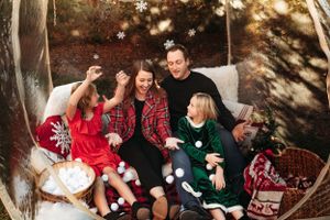 Large family in coordinating holiday outfits sitting in an outdoor bed for a Christmas photo session with L. Ballenger Photography.
