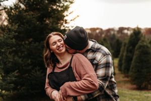 Couple hugging in an evergreen forest during a winter-themed photo session in Branson with L. Ballenger Photography.