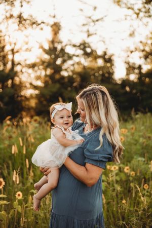 Mother and baby daughter in a golden hour field during a lifestyle photo session with L. Ballenger Photography.