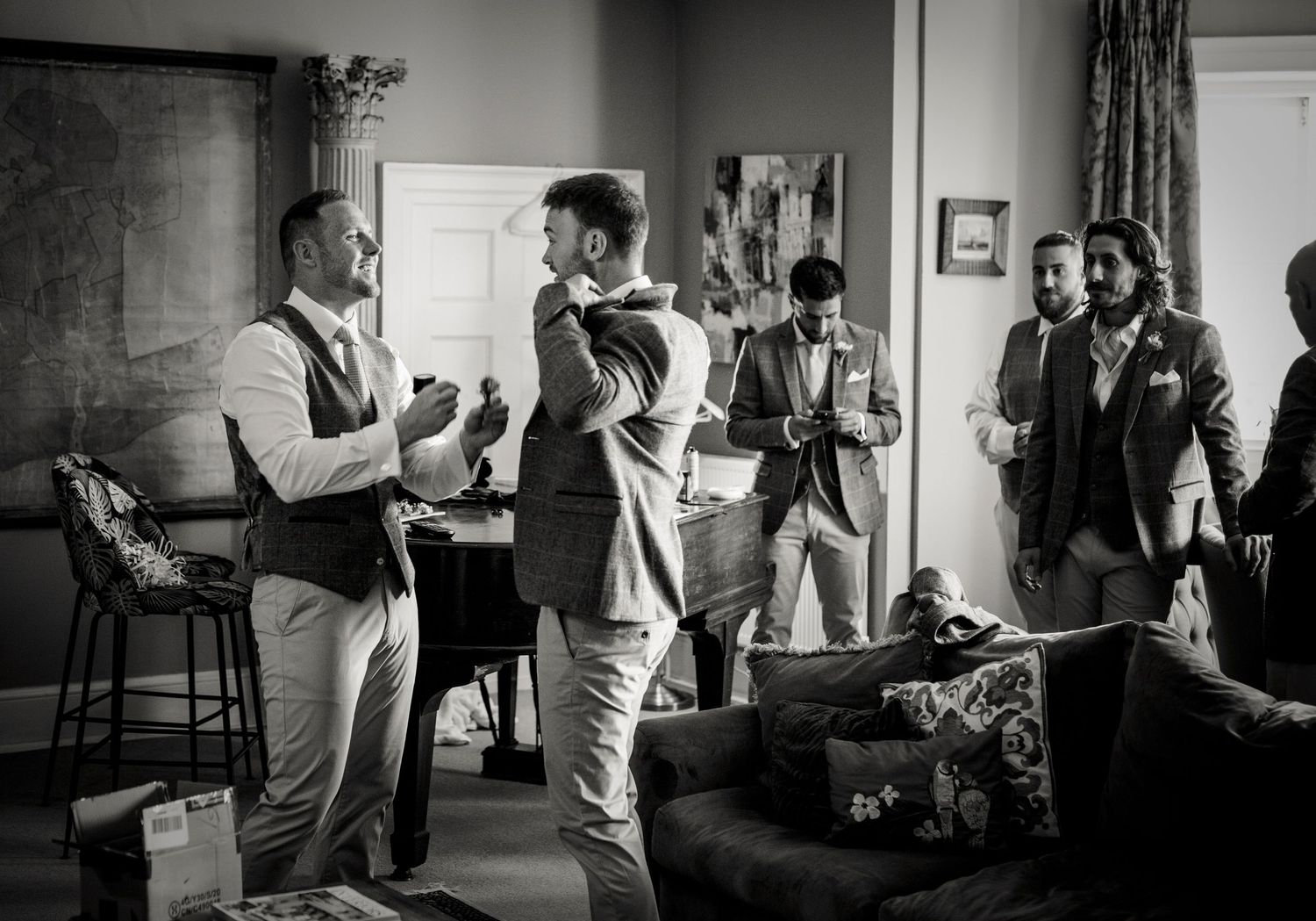 A black and white photo captures wedding party preparations in a casual indoor setting.