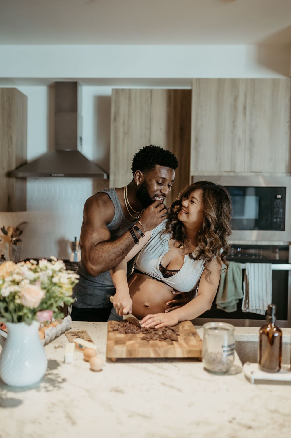 Couple shares playful moment while cooking together in modern kitchen.