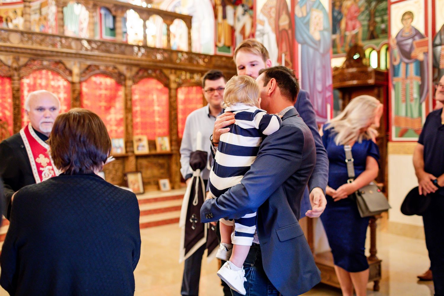 A religious ceremony takes place inside an ornate church with decorated walls and archways.