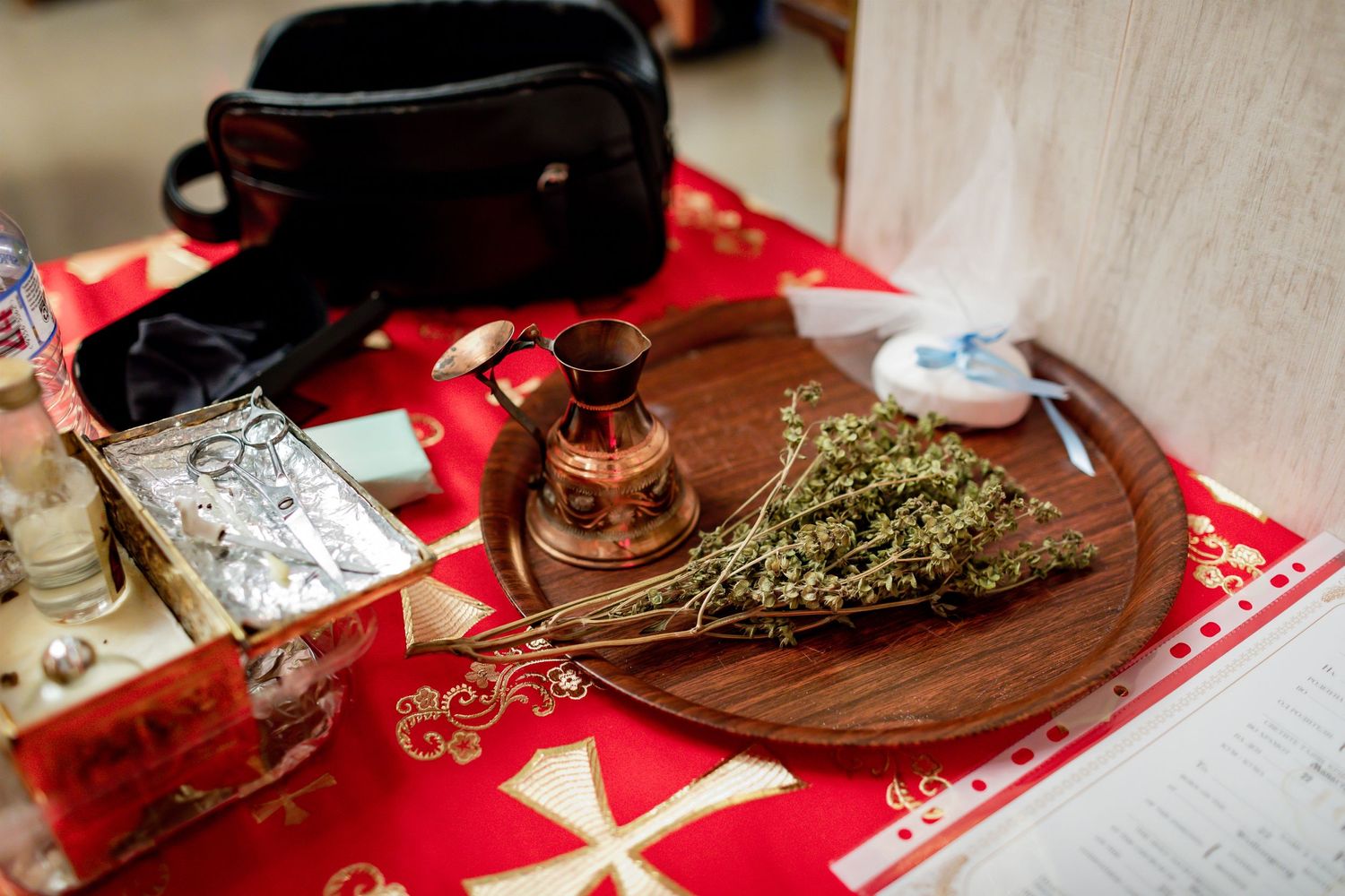 Religious ceremonial items arranged on a red cloth including incense, candles, and dried herbs.