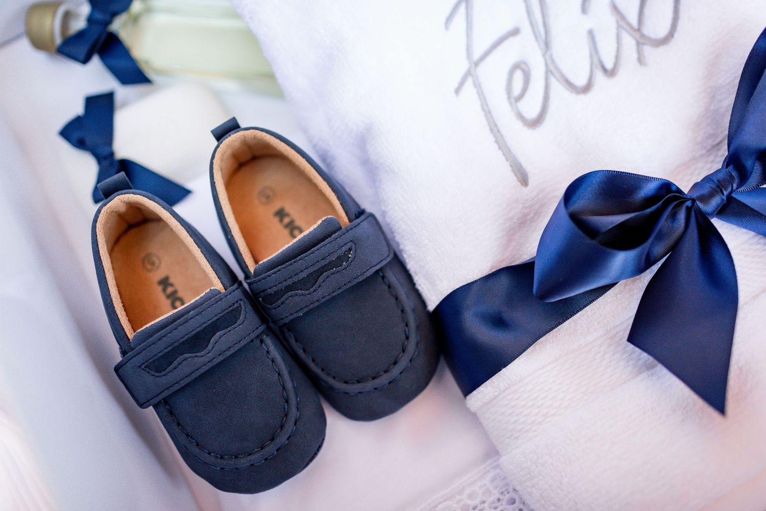 Navy blue baby loafers with matching bow decorations displayed on white fabric.