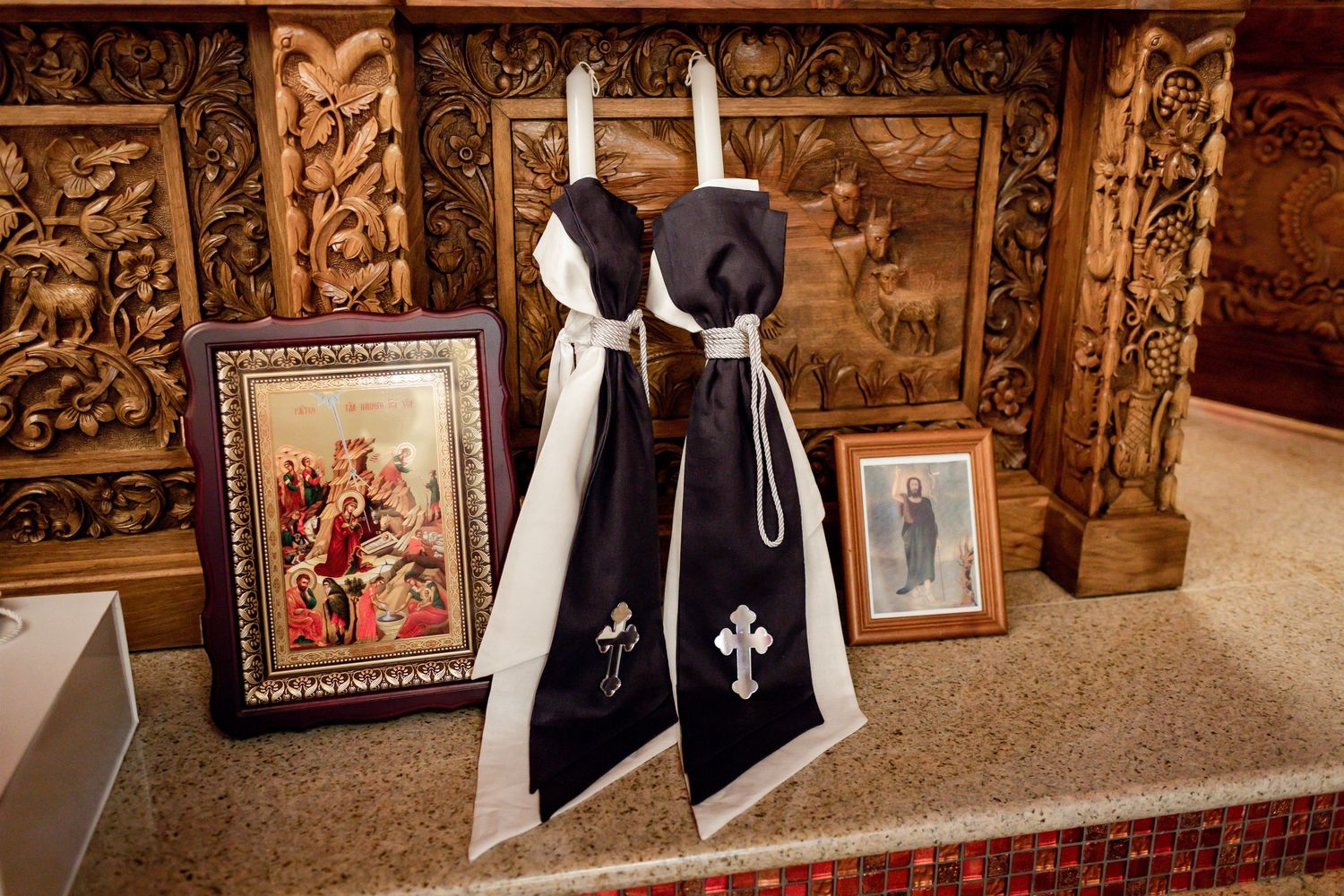 Black and white ceremonial garments displayed against carved wooden panels with framed artwork.