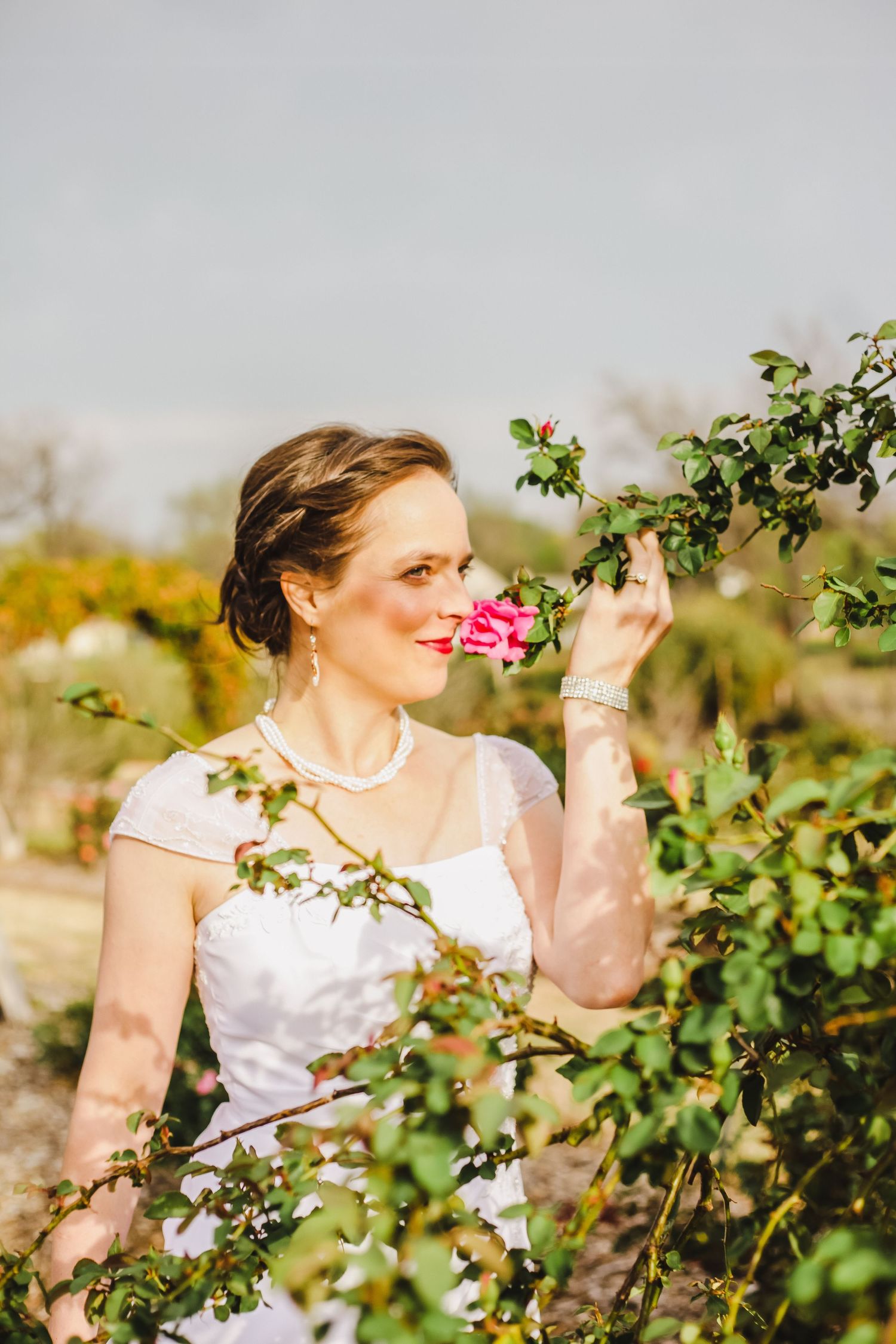 A white dress against green foliage in a garden setting creates an elegant outdoor portrait.