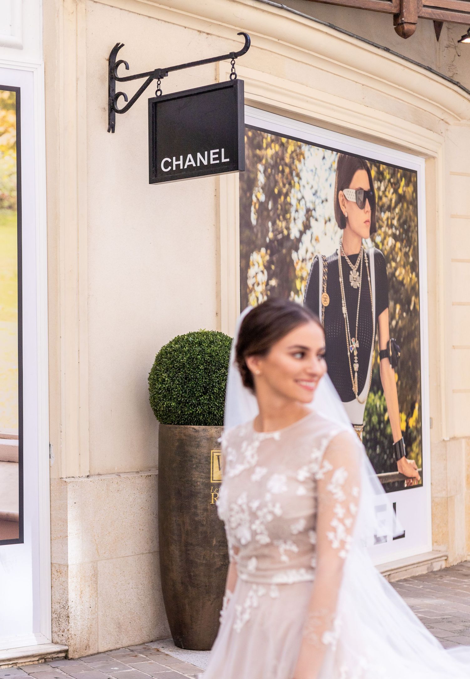 A bridal fashion scene outside a Chanel boutique with elegant storefront decor.