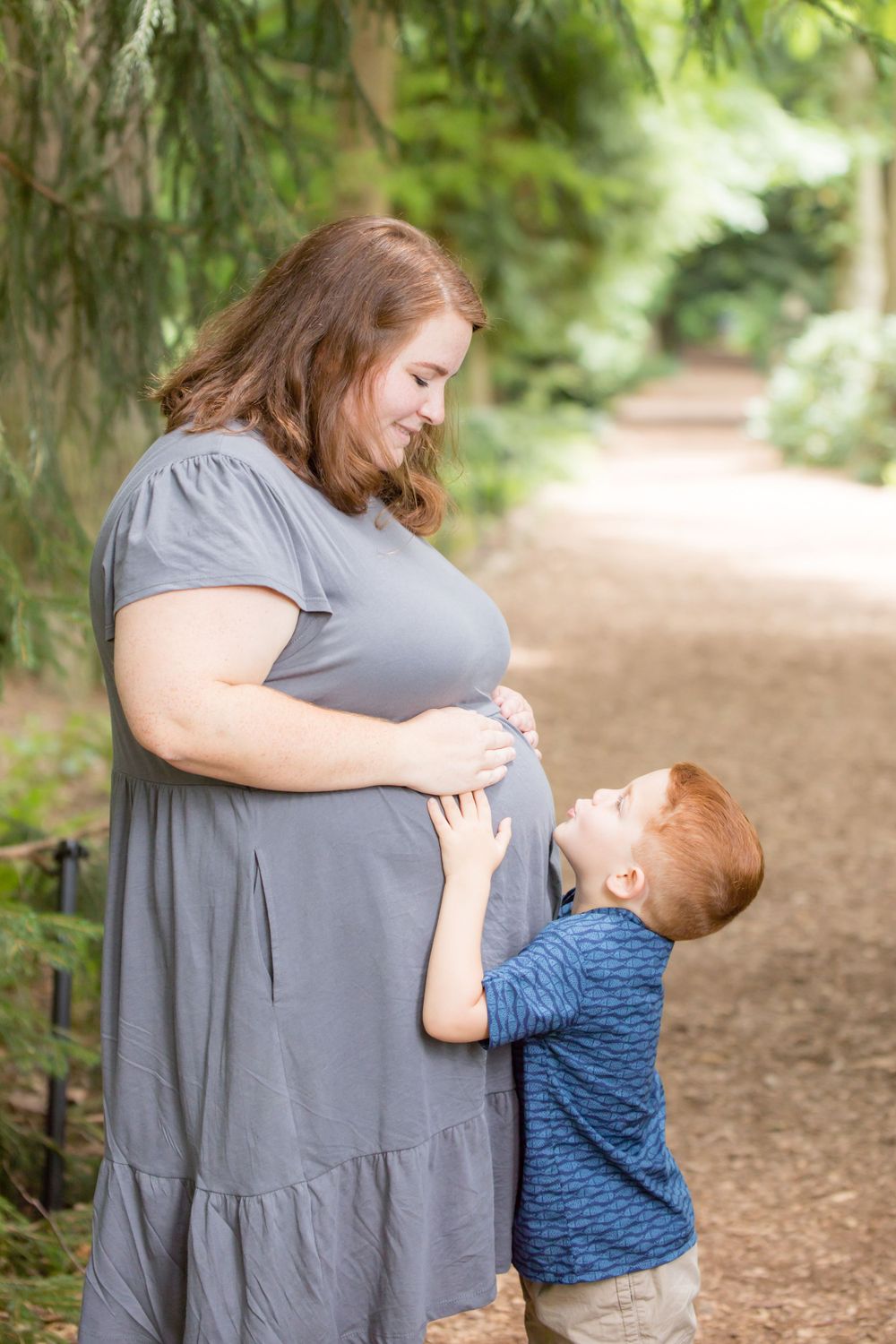little boy hugging his moms pregnant belly for pregnancy announcement session at Longwood gardens Pennsylvania