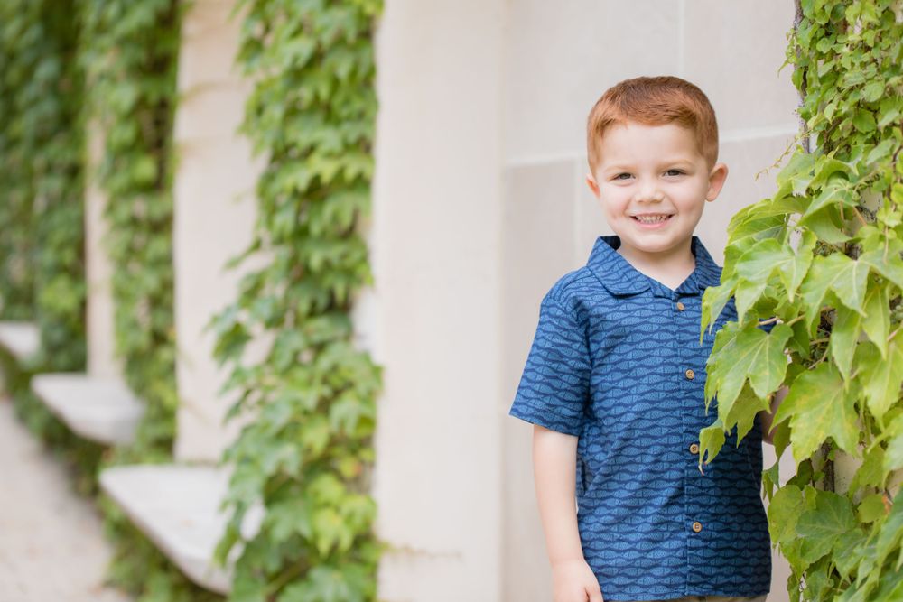 redheaded male child by ivy on sandstone fountain smiling at camera at Longwood gardens Pennsylvania