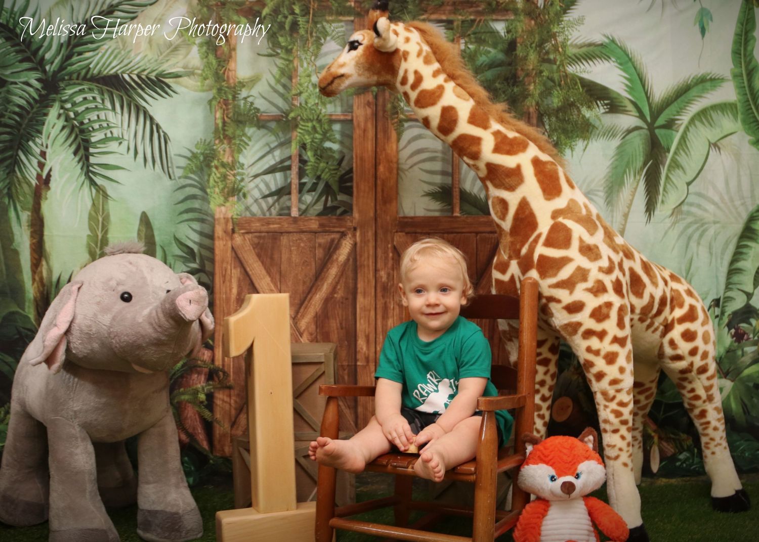 Safari-themed first birthday setup with stuffed giraffe, elephant, and fox toys.