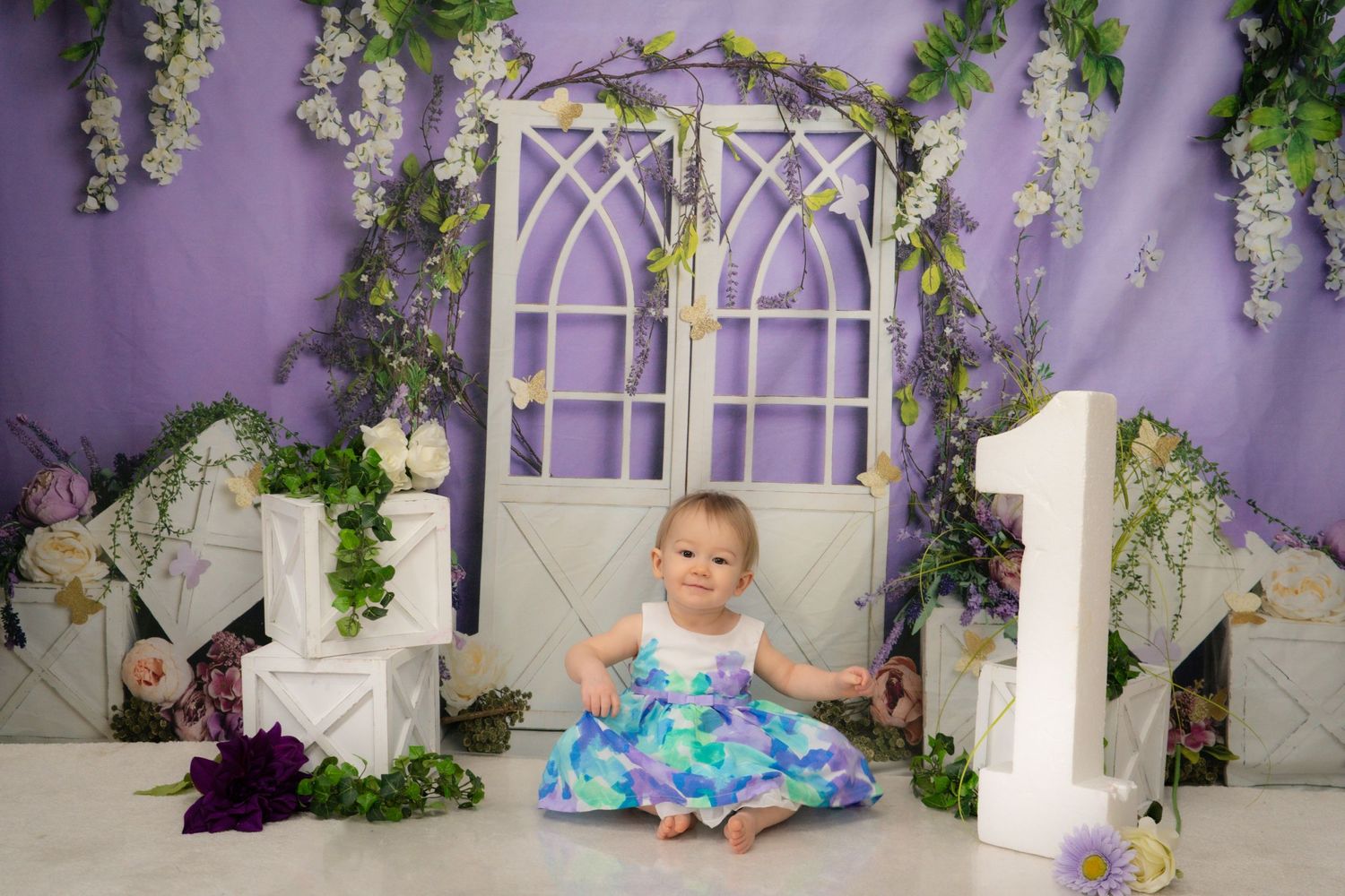 A whimsical garden-themed photo setup with arched windows, wisteria, and floral decor against a purple backdrop.