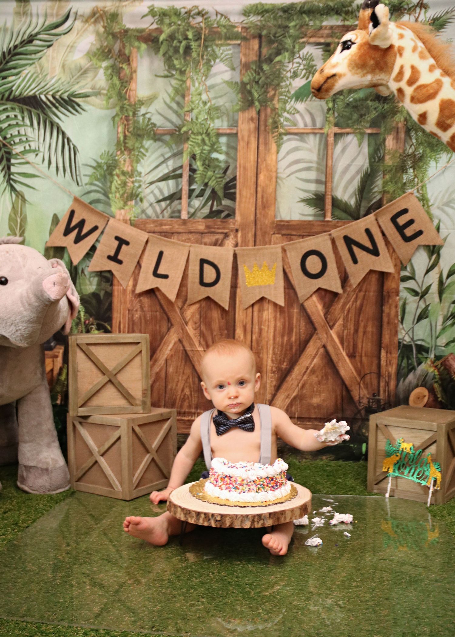 Safari themed first birthday setup with giraffe decoration and 'WILD ONE' banner.