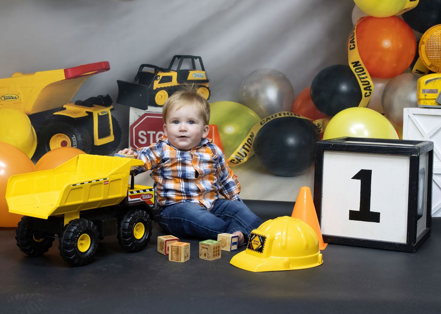 Construction-themed birthday setup with toy trucks, balloons and number one display.