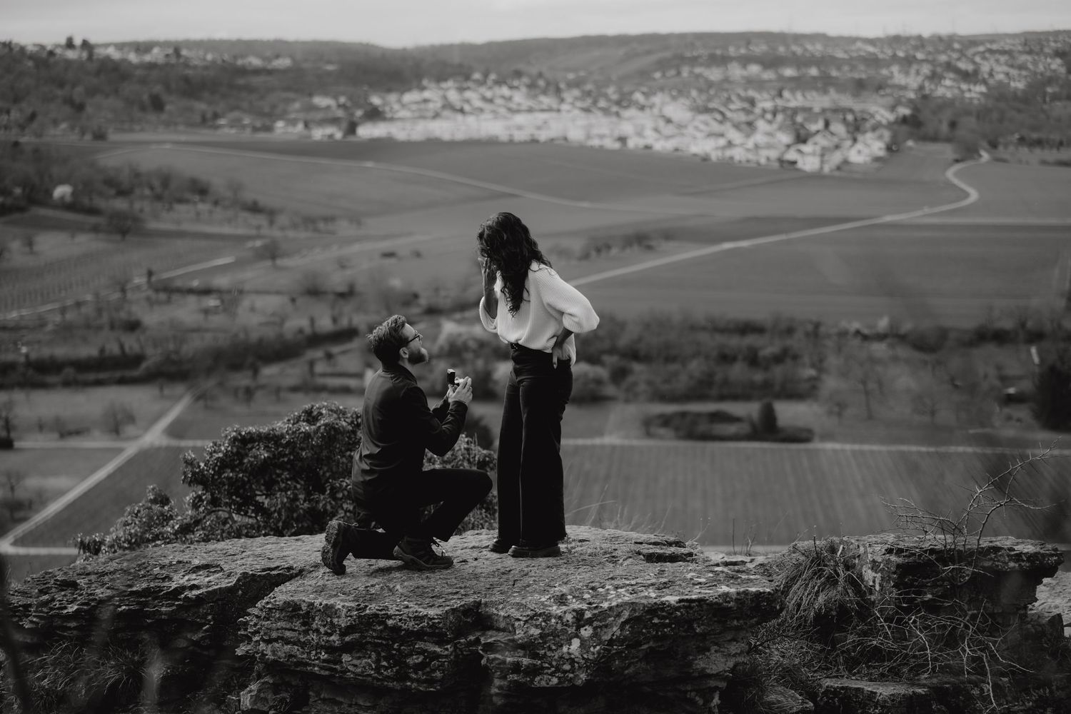 Vintage black and white photo of two figures on a scenic cliff overlook.