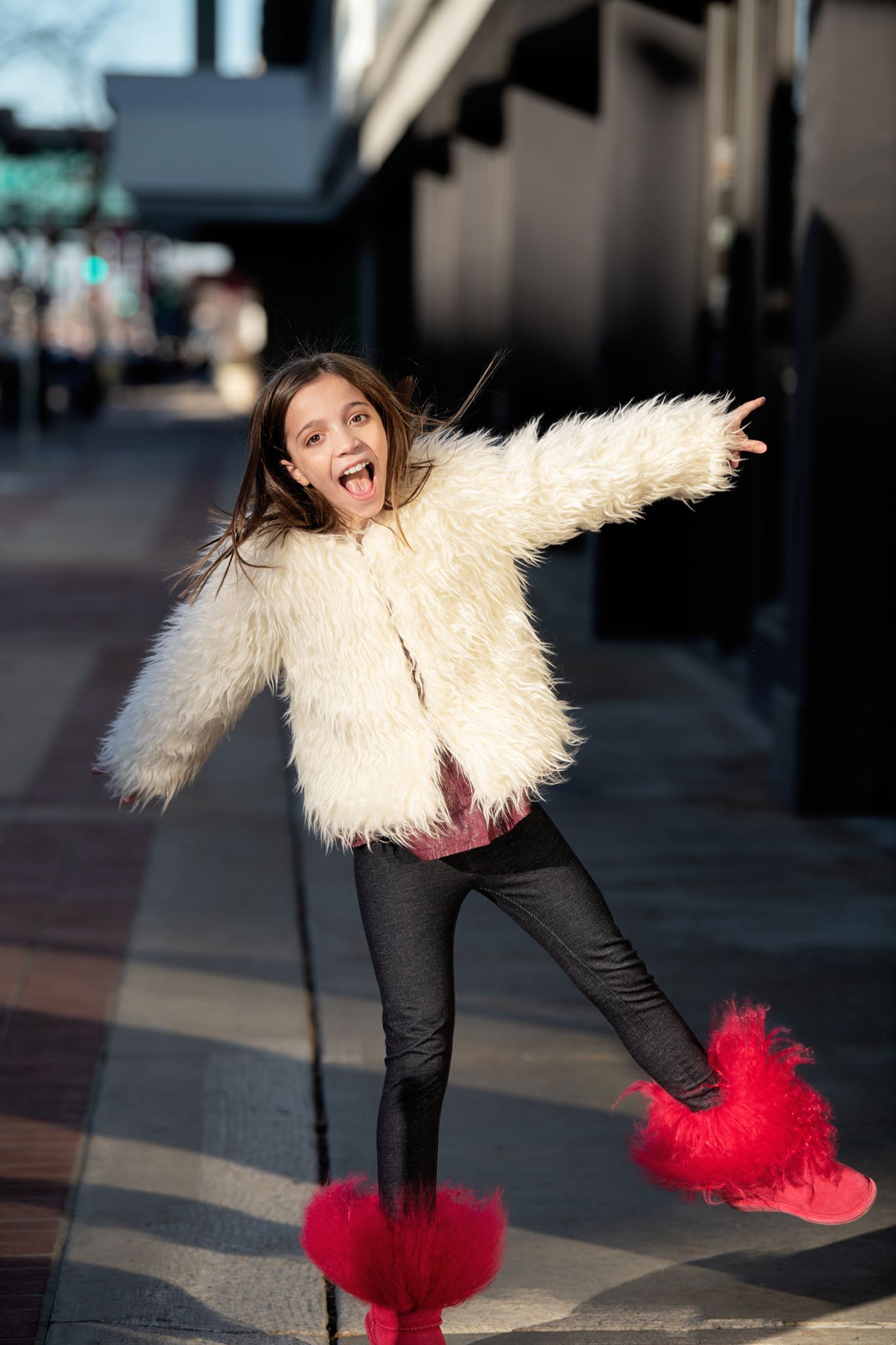 Energetic street scene with fluffy white coat and red fuzzy boots showing joyful movement.