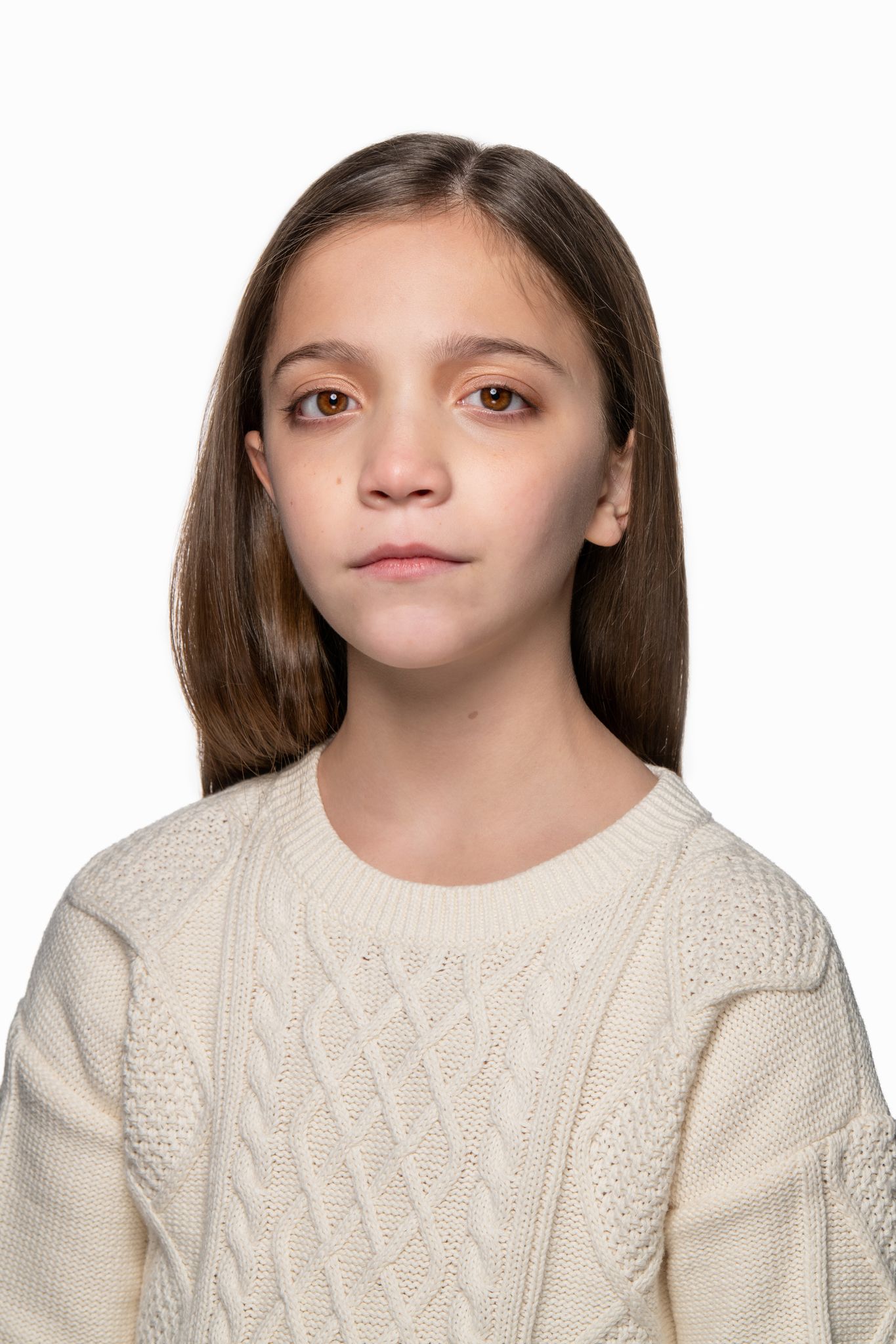 Studio portrait in cream cable knit sweater with neutral expression against white background.