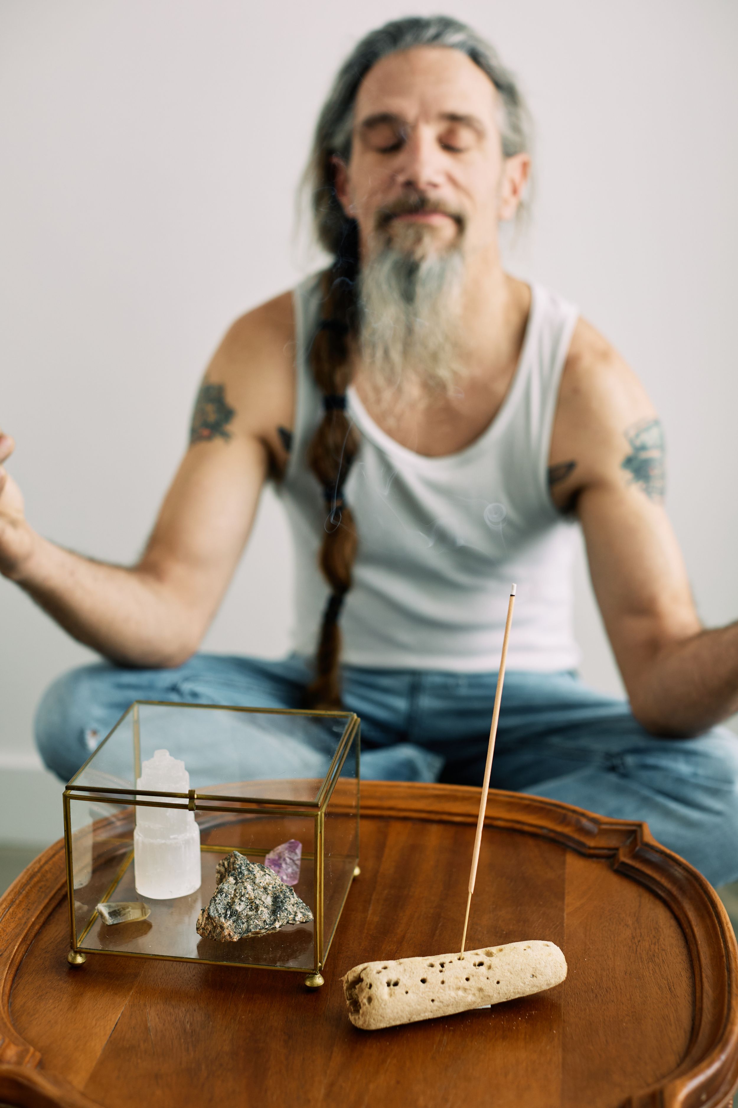 Person gesturing while sitting at table with various objects.