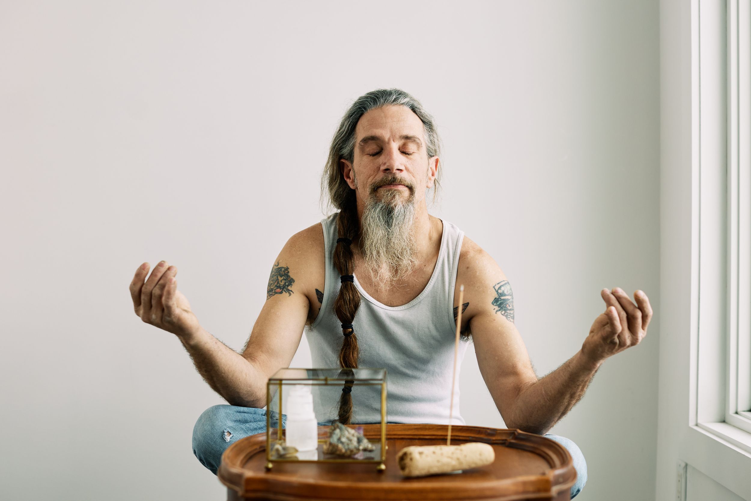 Person making expressive gestures while seated at wooden table.