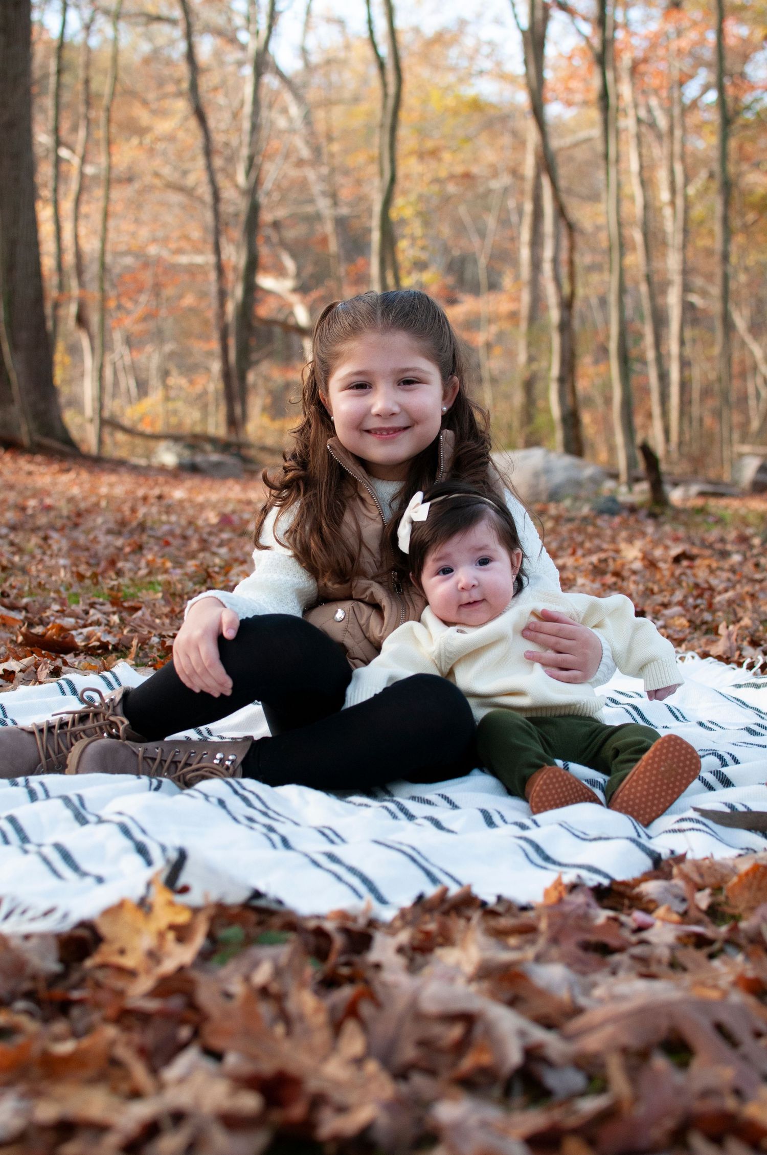 Young girl and baby sitting on blanket in fall