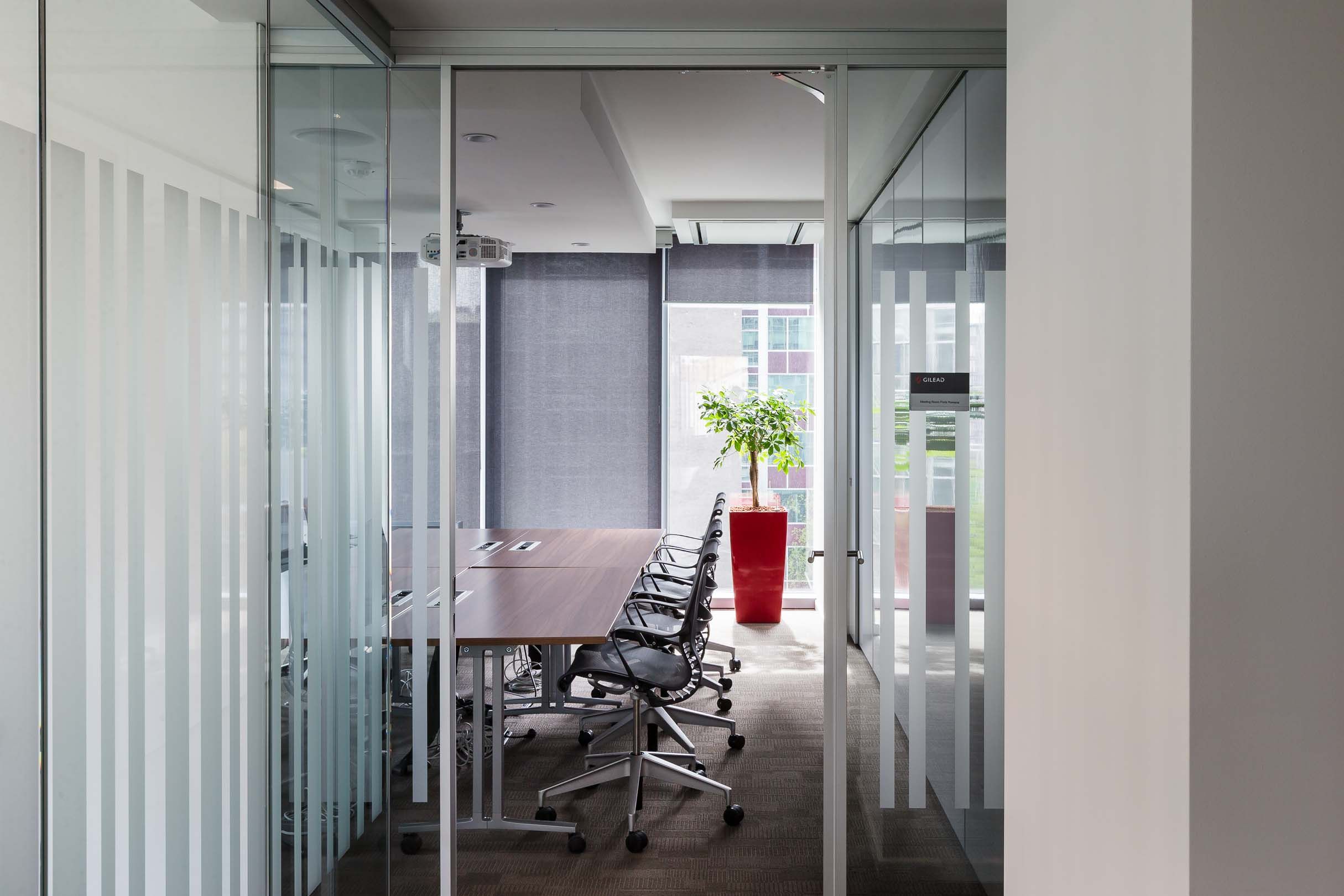 Glass-walled conference room with modern ergonomic chairs and a sleek meeting table.
