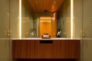 Elegant bathroom vanity with wooden panels, vertical lighting, and symmetrical mirrors.