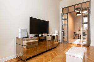 Modern living room featuring a wooden TV cabinet with herringbone flooring and glass partition wall.
