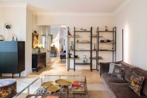 Open concept living space with industrial shelving, grey sofa, and vintage decor elements.