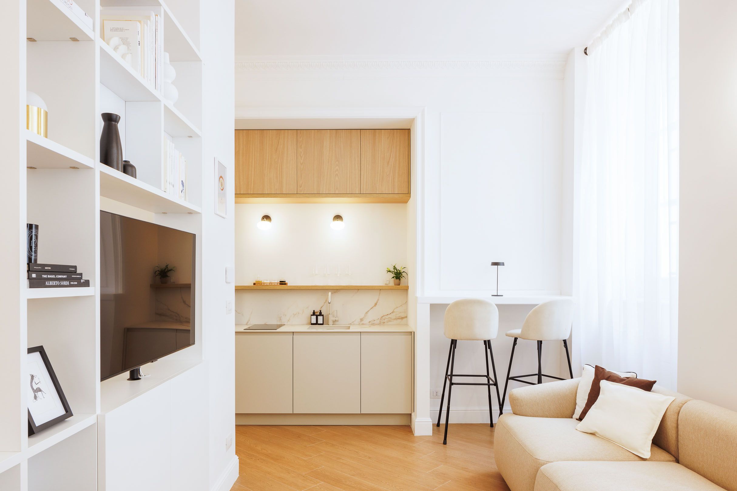 Contemporary white living room with built-in storage and small kitchen nook.