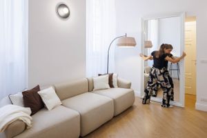 Modern living room with beige sectional sofa and circular wall sconce.