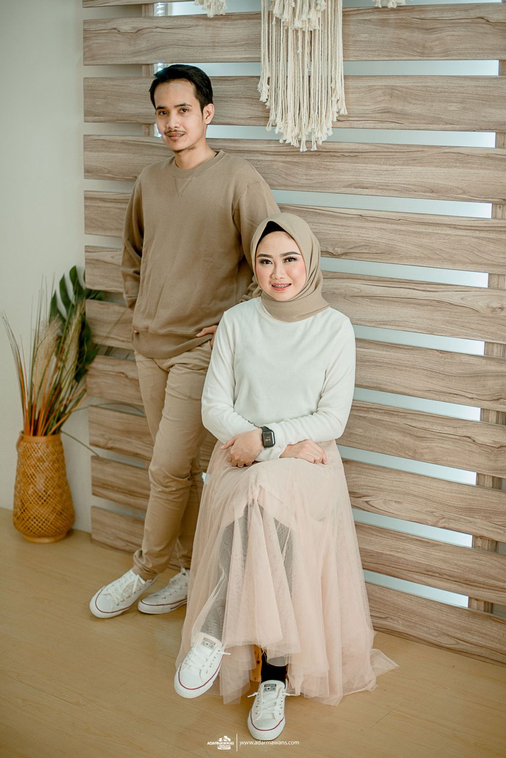Lifestyle portrait against wooden slat wall with macrame hanging decor.